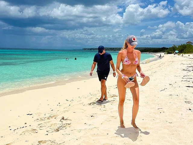 People walking on a beautiful white sand beach with clear water.