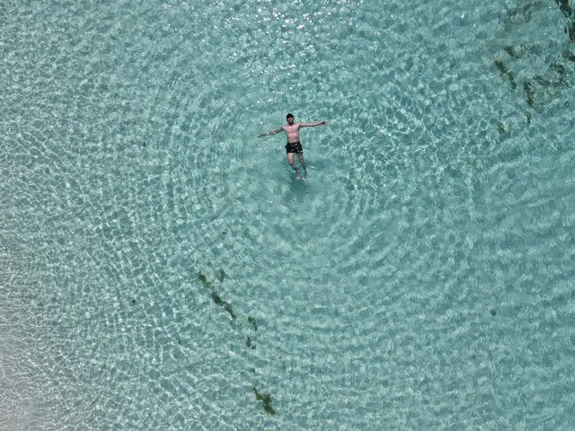 Vista aérea de una persona flotando en aguas turquesa cristalinas.